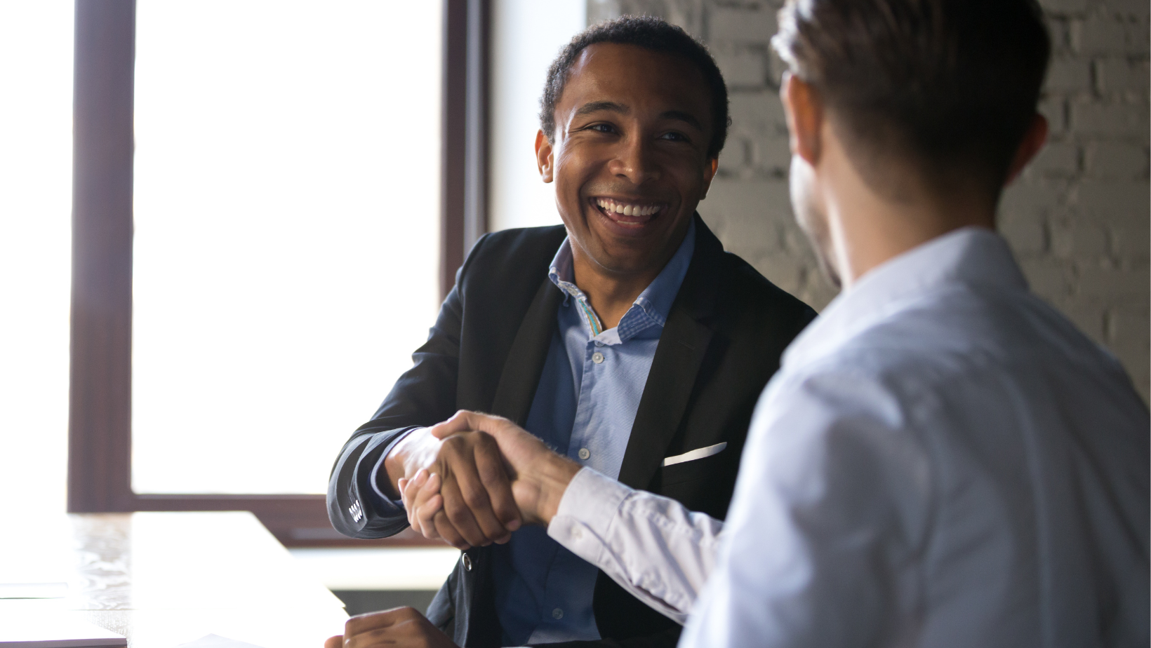 African American entrepreneur shaking hands with another young entrepreneur in an office setting