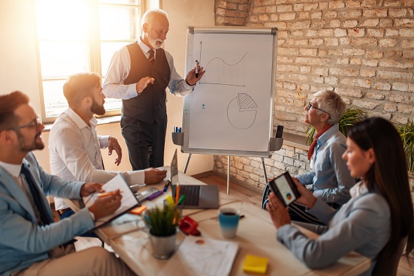 Older businessman presenting to a group of co-workers