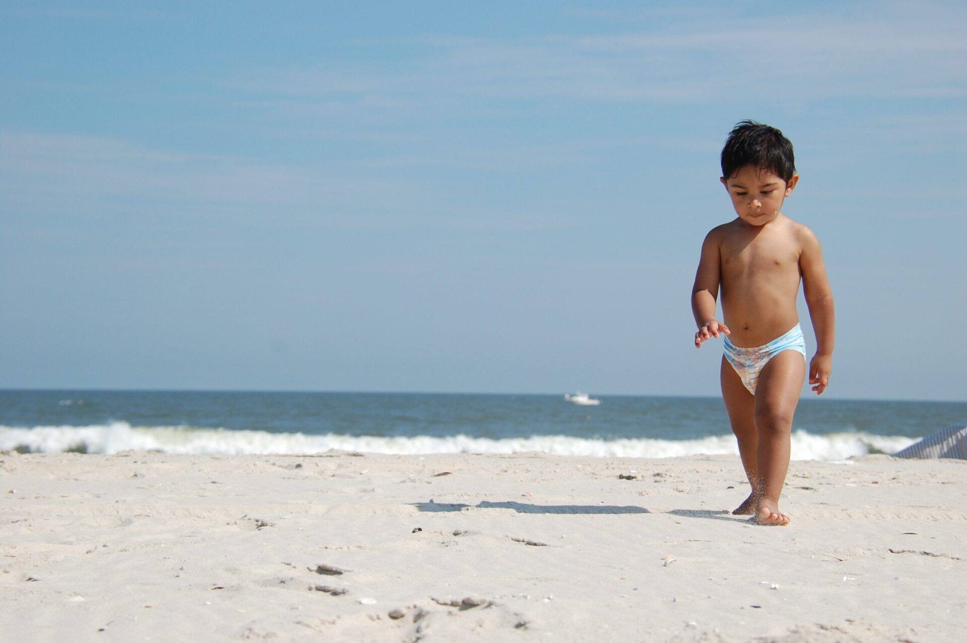 Toddler in a diaper walking along the beach