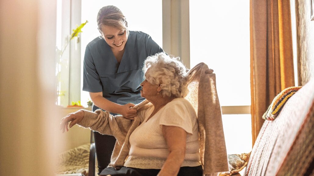 Caregiver helping a senior get dressed at home